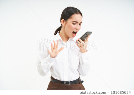 Angry business woman shouts at mobile phone, has intense conversation on telephone, stands over white background 101685634