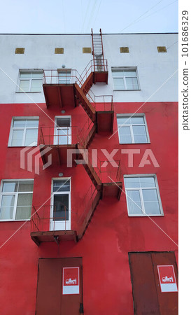 The facade of a red house with an iron fire escape. 101686329