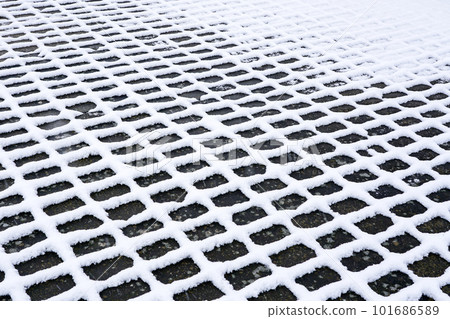A checkered outline snowy pattern on dark cobblestones, perspective view on snow texture A checkered outline snowy pattern on dark cobblestones, perspective view on snow texture 101686589