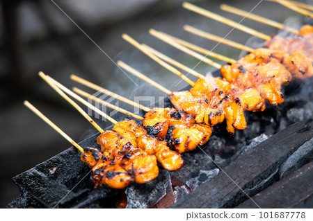 Closeup of chicken satay being barbecue with traditional pit and fired with charcoal 101687778
