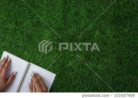 A person writing on a notebook on a field of grass A person writing on a notebook on a field of grass 101687989