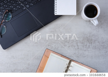 將膝上型電腦和筆記本放在桌子上，一邊喝咖啡一邊做案頭工作的圖片 101688658