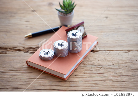 Money piled up on a book (yen) 101688973
