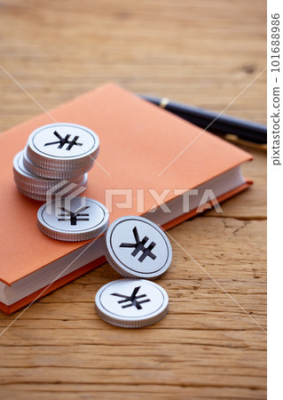Money piled up on a book (yen) 101688986