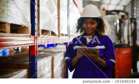 Afro woman staff wearing vest and safety helmet and walking count the box at storehouse 101690184