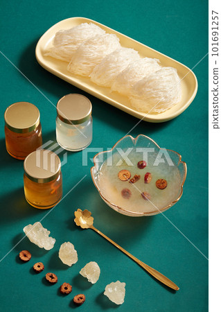 Bird nest on dishes, bowl soup, jujube, rock sugar and glass bottles without label on green background. Healthcare food, have effects: Anti-neurasthenia and increase the body's resistance Bird nest on dishes, bowl soup, jujube, rock sugar and glass bottles without label on green background. Healthcare food, have effects: Anti-neurasthenia and increase the body's resistance 101691257