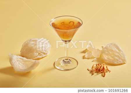 Glass cup of bird nest distilled with cordyceps and rock sugar on beige background. Bird nest and cordyceps are expensive culinary ingredient for health Glass cup of bird nest distilled with cordyceps and rock sugar on beige background. Bird nest and cordyceps are expensive culinary ingredient for health 101691266