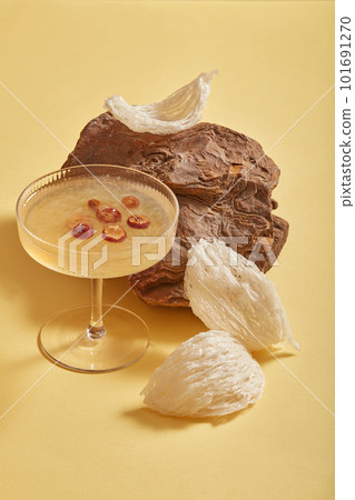 Advertising photo for product with raw bird nest on stone, glass cup of bird nest and jujube soup on beige background. Healthcare food and herbs, popular at Vietnam, China and Asia 101691270