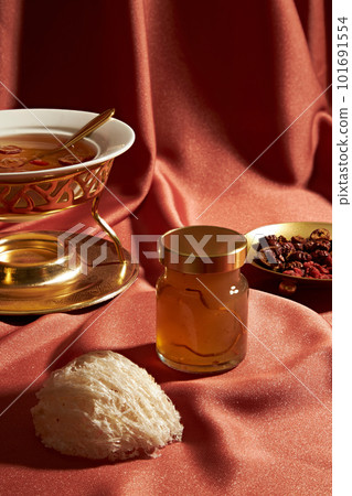 Front view of a bottle of bird nest unlabeled, raw bird nest and jujube, wolf berry, soup on a red soft fabric background. Mockup scene advertising bird nest products are distilled with herbs Front view of a bottle of bird nest unlabeled, raw bird nest and jujube, wolf berry, soup on a red soft fabric background. Mockup scene advertising bird nest products are distilled with herbs 101691554