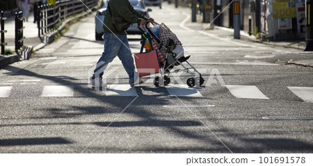 A man pushing a stroller across the pedestrian crossing A man pushing a stroller across the pedestrian crossing 101691578