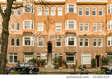 a brick apartment building with bicycles parked in front and two cars parked on the street next to each other buildings a brick apartment building with bicycles parked in front and two cars parked on the street next to each other buildings 101691914