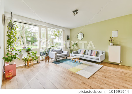 a living room with green walls and wood flooring in the middle of the room, there is a white couch on the right 101691944