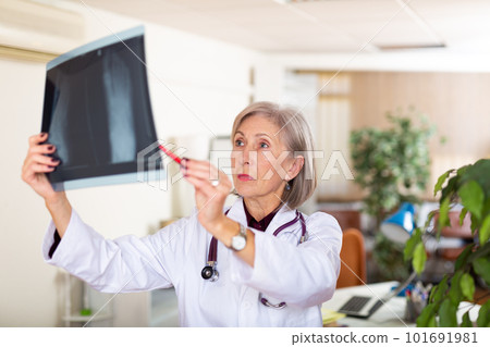 Female doctor examining x-ray closely in clinic closeup 101691981