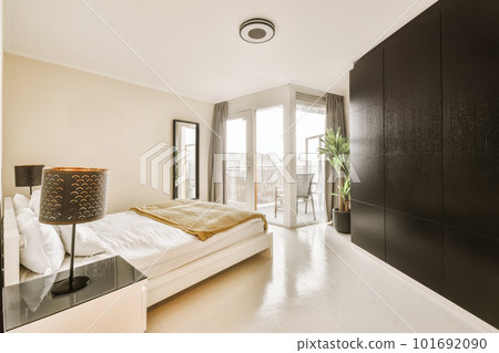 a bedroom with a large bed and black cabinetd cupboards on the wall next to the window in the room a bedroom with a large bed and black cabinetd cupboards on the wall next to the window in the room 101692090