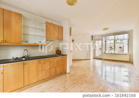 a kitchen area with wood cabinets and white tile on the walls, along with an open door leading to another room 101692108