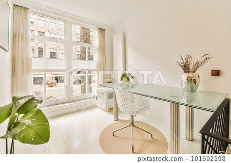 a room with a desk, chair and large window looking out onto the street in front of the apartment building 101692198