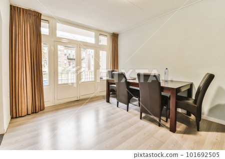 a dining table and chairs in a living room with sliding glass doors leading to the balcony area, which can be used as a 101692505