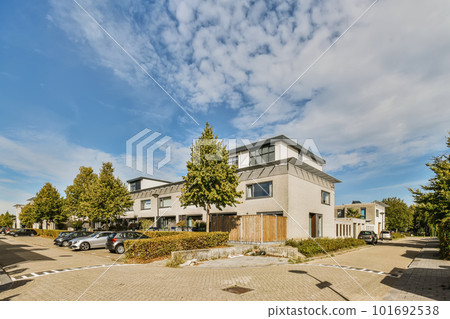 a house in the middle of an urban area with cars parked on the driveway and trees lining the side of the street a house in the middle of an urban area with cars parked on the driveway and trees lining the side of the street 101692538