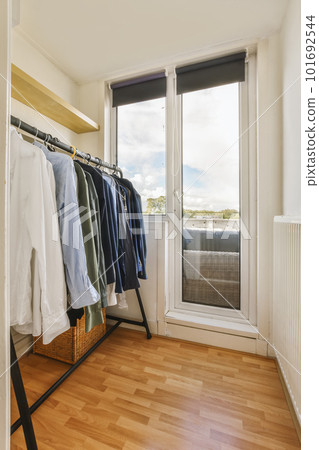 some clothes hanging on a rack in a room with wood flooring and large windows looking out onto the street some clothes hanging on a rack in a room with wood flooring and large windows looking out onto the street 101692544