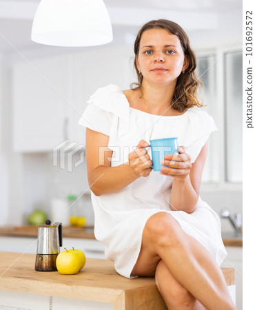 Woman drinking coffee in kitchen at home Woman drinking coffee in kitchen at home 101692572