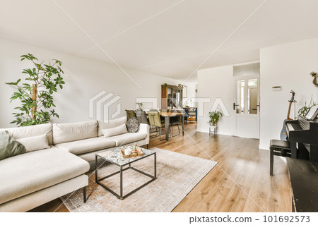 a living room with a piano in the corner and an open door leading into the dining area on the right side 101692573