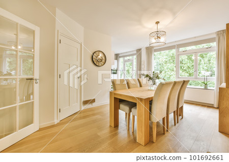 a dining room with wood flooring and white trim on the walls, there is a large mirror in the window 101692661