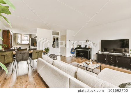 a living room with wood flooring and white couches in front of the sofa is an open kitchen area a living room with wood flooring and white couches in front of the sofa is an open kitchen area 101692700