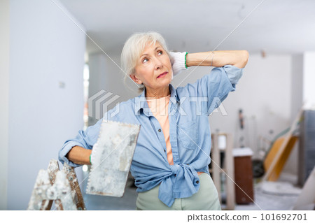 Portrait of positive woman with spatula in her hand in room being renovated Portrait of positive woman with spatula in her hand in room being renovated 101692701