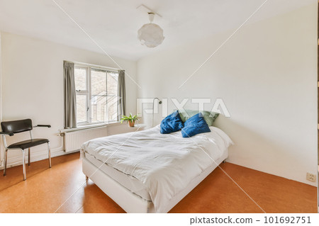 a bedroom with a bed, chair and desk in the corner of the room on the right is a window 101692751