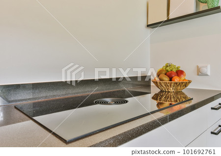 a bowl of fruit sitting on the kitchen counter in front of a sink that is white and has black granite 101692761