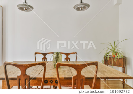 a dining table and chairs in a room with white walls, wood floors and wooden flooring there is a plant on the wall 101692782