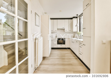a long narrow kitchen with white cabinets and appliances on the wall, as seen from the doorway leading to the dining area 101692806