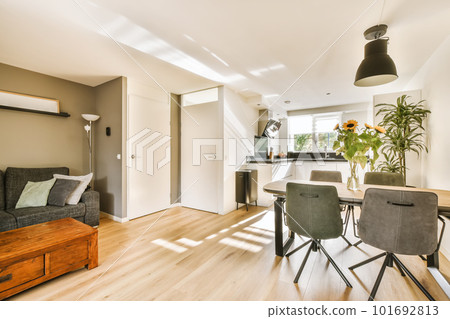 a living room with wood flooring and white walls, including a dining table and two chairs in front of the couch 101692813