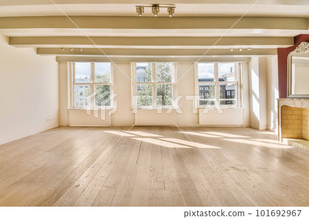 an empty living room with wood flooring and large windows in the room is very clean, but there is no light an empty living room with wood flooring and large windows in the room is very clean, but there is no light 101692967