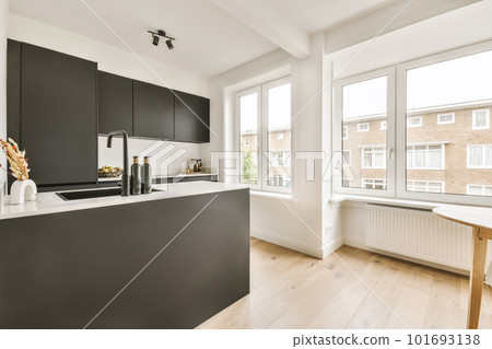 a modern kitchen with black cabinets and white countertops in the center of the image is an open window overlooking outside a modern kitchen with black cabinets and white countertops in the center of the image is an open window overlooking outside 101693138