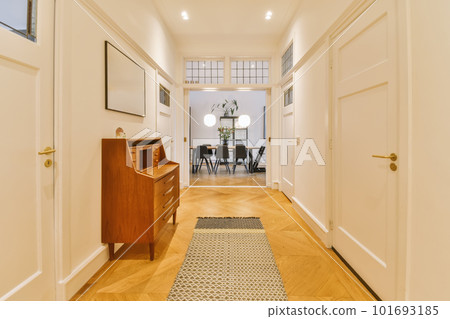 a long hallway with hardwood flooring and white trim on the walls, there is a small desk in the corner 101693185