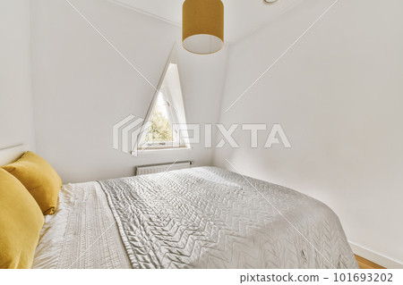 a bedroom with white walls and wood flooring the room has a large bed, yellow throw pillows on it 101693202