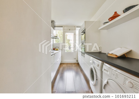a laundry room with wood flooring and white washer in the area is well lit by natural light from the window 101693211