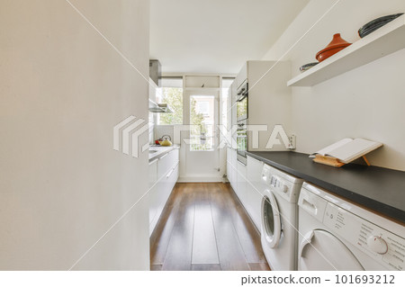 a laundry room with wood flooring and white washer in the area is well lit by natural light from the window a laundry room with wood flooring and white washer in the area is well lit by natural light from the window 101693212
