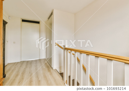 an empty room with white walls and wood railings on the bottom floor, there is a wooden staircase leading up to the second an empty room with white walls and wood railings on the bottom floor, there is a wooden staircase leading up to the second 101693214