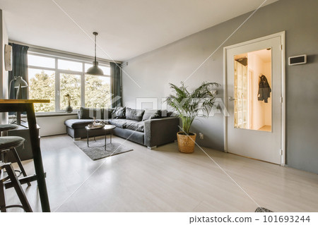 a living room with grey walls and wood flooring in the center of the room is an open door leading to a dining area a living room with grey walls and wood flooring in the center of the room is an open door leading to a dining area 101693244