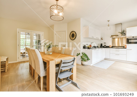 a kitchen and dining area in a house with white walls, hardwood flooring and light wood table surrounded by chairs a kitchen and dining area in a house with white walls, hardwood flooring and light wood table surrounded by chairs 101693249
