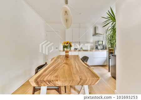 a kitchen and dining area in a house with white walls, hardwood flooring and an island table surrounded by wooden chairs 101693253