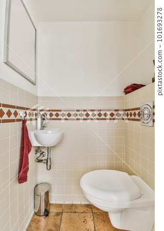 a white toilet in a small bathroom with tiled walls and brown tile on the floor, there is a mirror above it 101693278