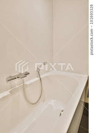 a white bathtub in the corner of a bathroom with black tiles on the walls and flooring around it a white bathtub in the corner of a bathroom with black tiles on the walls and flooring around it 101693326