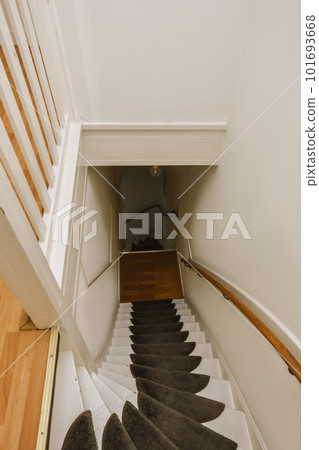 some stairs in a house that looks like it's going up to the ceiling and there is carpet on the floor 101693668