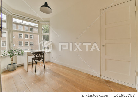 Amsterdam, Netherlands - 10 April, 2021: an empty room with a chair and table in front of a large window looking out onto the street below it 101693798