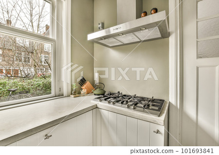 a kitchen with white cabinets and counter space in front of the window that looks out onto an urban neighborhood street 101693841