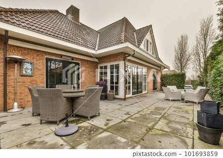 a patio with wickers, chairs and an umbrella on the ground in front of a bricked house a patio with wickers, chairs and an umbrella on the ground in front of a bricked house 101693859