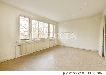 an empty room with white walls and wood flooring, there is a large window that looks out onto the street 101693860